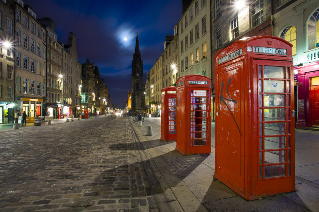Scotland, Edinburgh, The Royal Mile. Cobbled stone road and traditional red telephone boxes in the High Street, part of the historic Royal Mile in the Old Town.