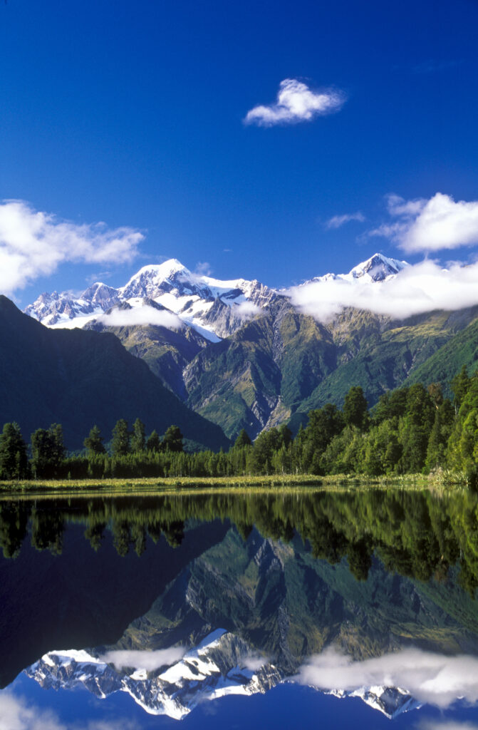 NEW ZEALAND, West Coast, Lake Matheson. Mt Cook and the southern Alps reflected in the still waters of the lake.
