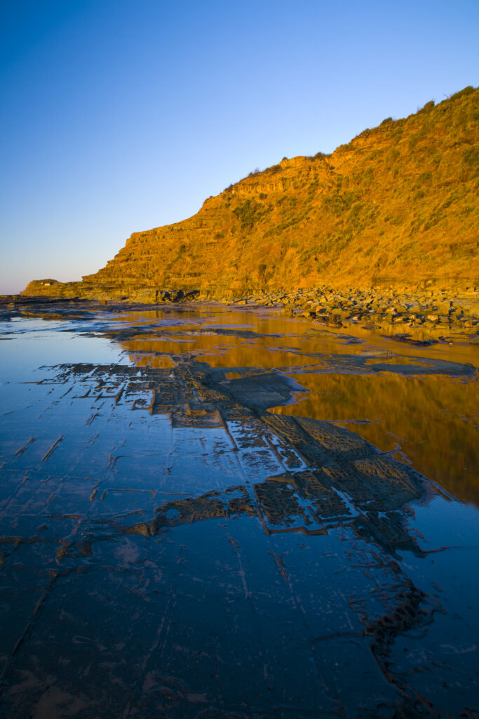 Australia, New South Wales, Royal National Park. Early morning light gently illuminates the picturesque coastline found at North Era, on the Royal National Park Coastal Track.