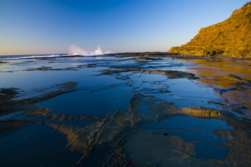 Australia, New South Wales, Royal National Park. Early morning light gently illuminates the picturesque coastline found at North Era, on the Royal National Park Coastal Track.