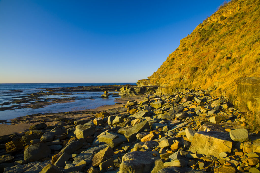 Australia, New South Wales, Royal National Park. Early morning light gently illuminates the picturesque coastline found at North Era, on the Royal National Park Coastal Track.