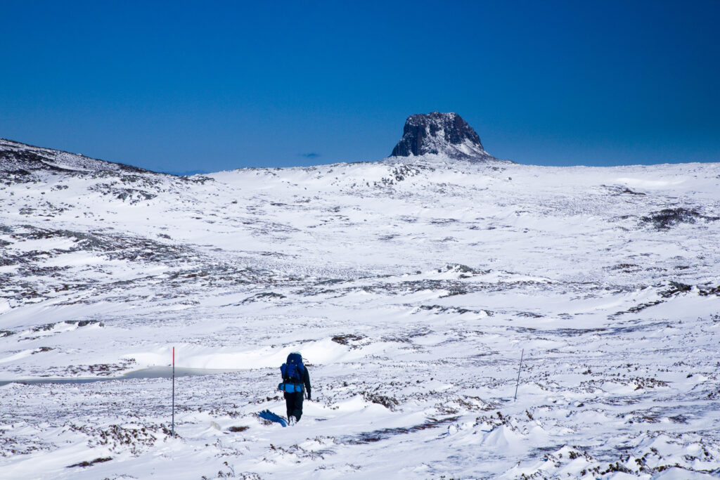 Australia, Tasmania, Cradle Mt - Lake St Clair National Park. Hiker walking towards Barn Bluff on the Overland Track, shortly after a spring snowfall.