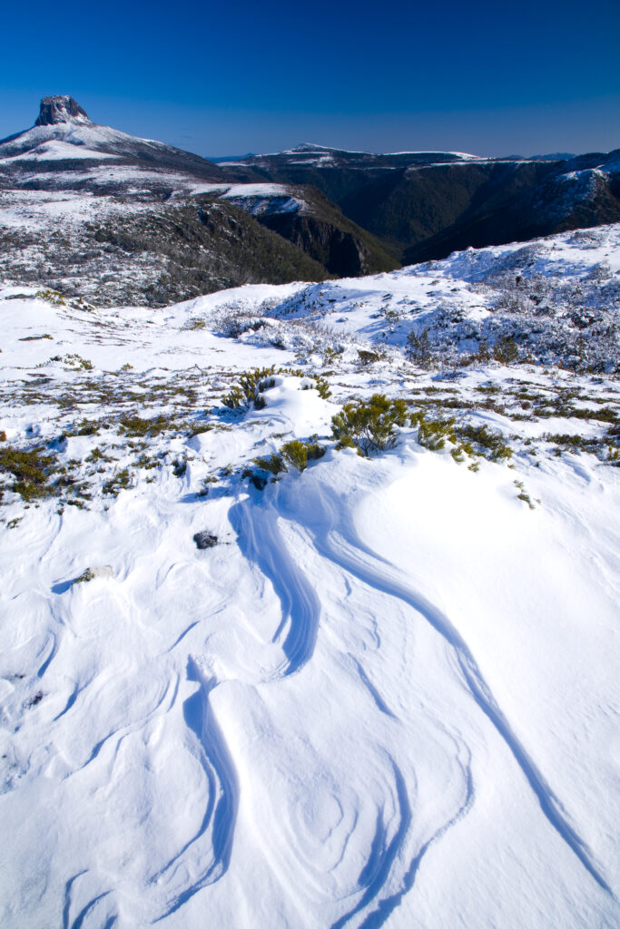 Australia, Tasmania, Cradle Mt - Lake St Clair National Park. Snow drifts on the Overland Track, with Barn Bluff in the distance.