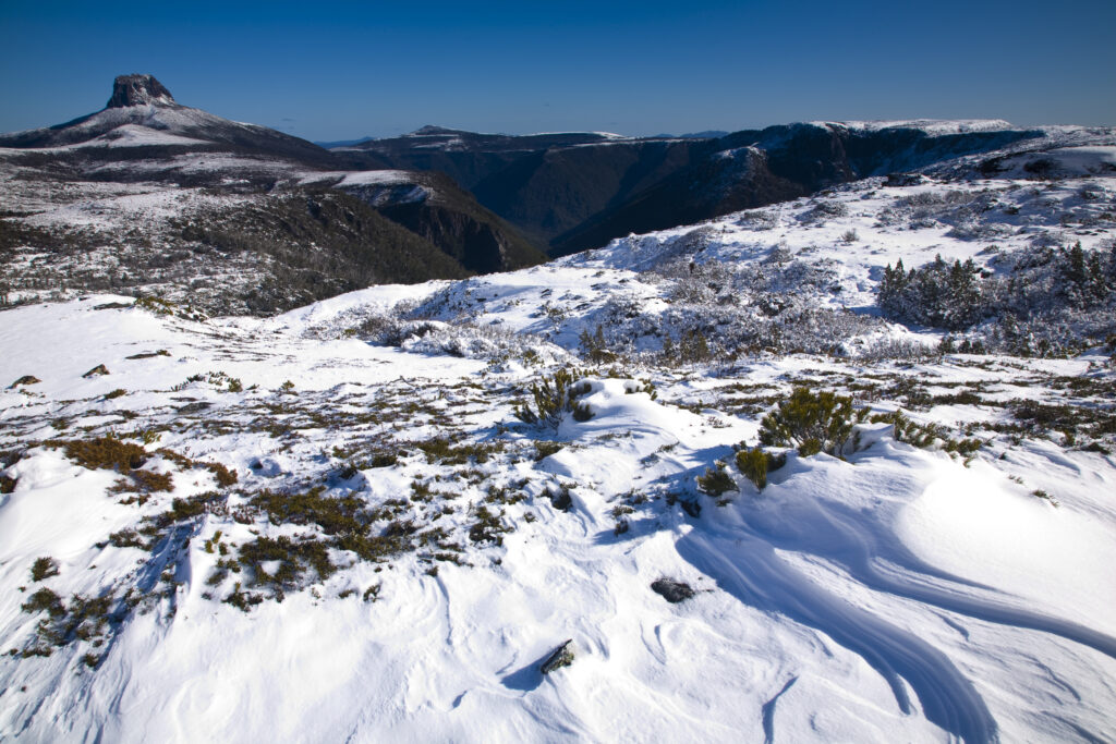Australia, Tasmania, Cradle Mt - Lake St Clair National Park. Snow drifts on the Overland Track, with Barn Bluff in the distance.