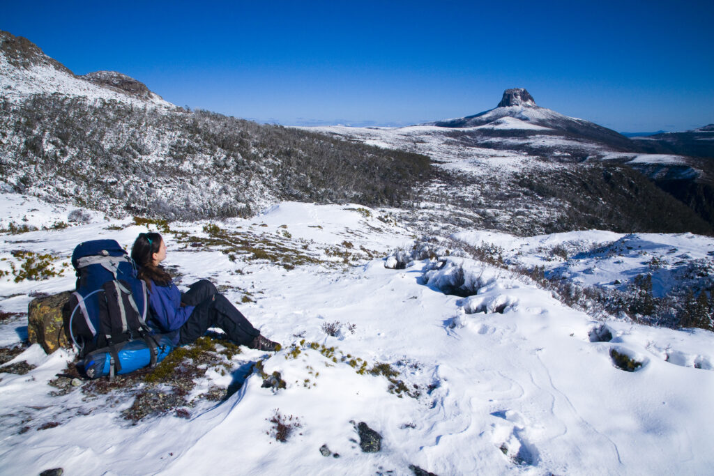 Australia, Tasmania, Cradle Mt - Lake St Clair National Park. Hiker walking the overland track takes a rest to enjoy the scenery.