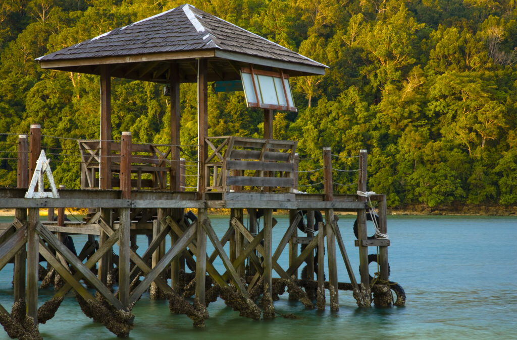 Borneo, Sabah Malaysia, Tunku Abdul Rahman Park. Wooden jetty on Sapi Island with the dense forest of nearby Gaya Island in the distance.