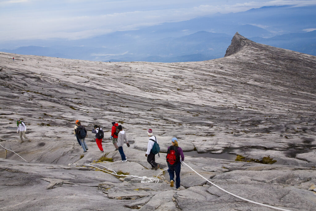 Sabah Malaysia, Borneo, Kinabalu National Park. Hikers descend the summit trail through the dramatic landscape of Mount Kinabalu - The highest mountain peak in South East Asia.