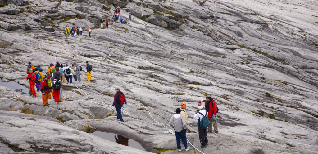 Sabah Malaysia, Borneo, Kinabalu National Park. Hikers descend the summit trail through the dramatic landscape of Mount Kinabalu - The highest mountain peak in South East Asia.
