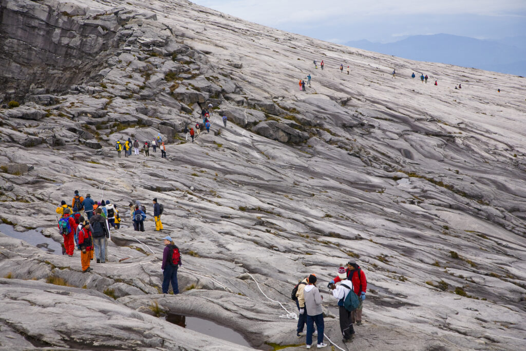 Sabah Malaysia, Borneo, Kinabalu National Park. Hikers descend the summit trail through the dramatic landscape of Mount Kinabalu - The highest mountain peak in South East Asia.