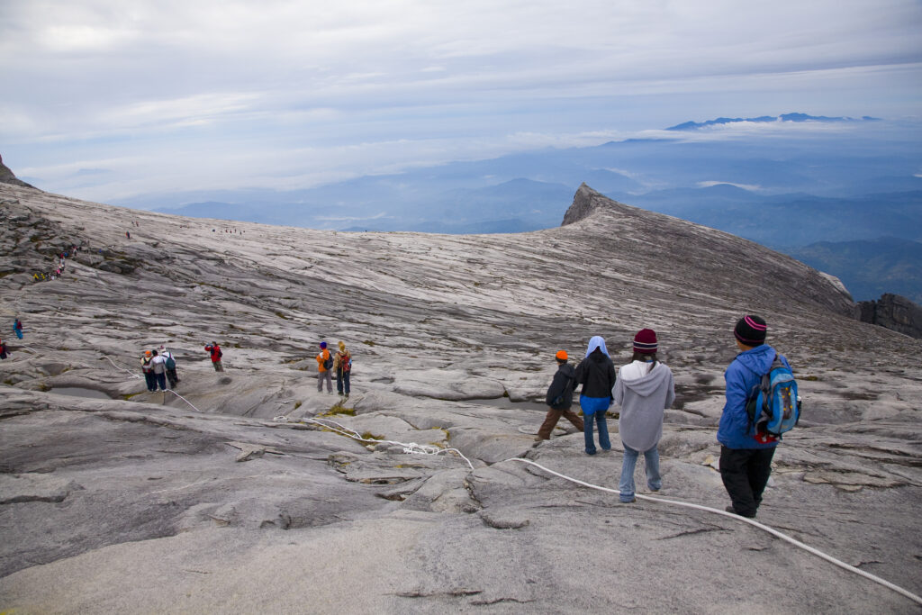 Sabah Malaysia, Borneo, Kinabalu National Park. Hikers descend the summit trail through the dramatic landscape of Mount Kinabalu - The highest mountain peak in South East Asia.