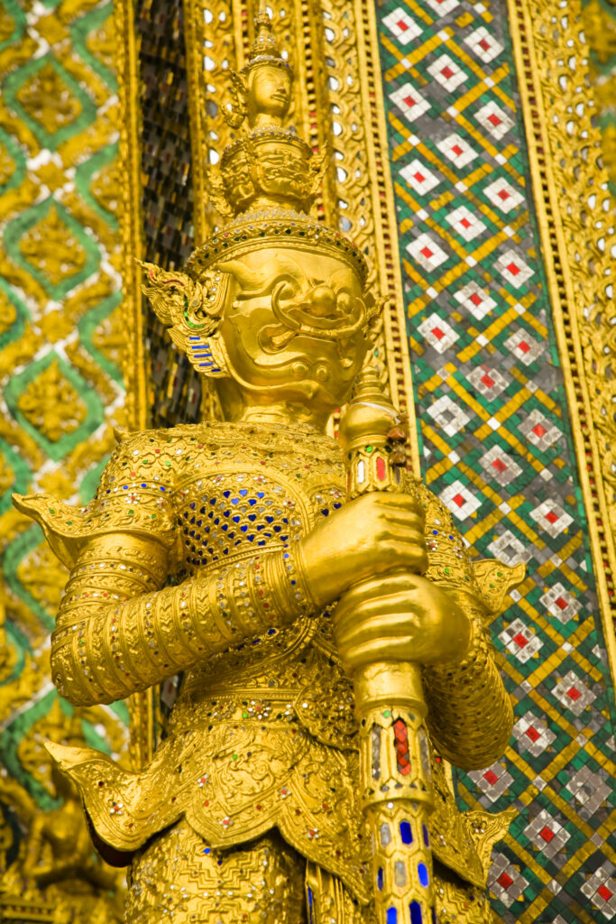 Thailand, Bangkok, The Grand Palace. Statue in the ornate setting of the golden grand palace.