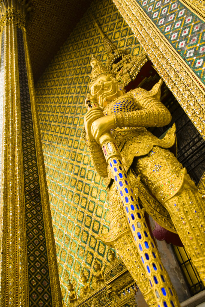 Thailand, Bangkok, The Grand Palace. Statue in the ornate setting of the golden grand palace.