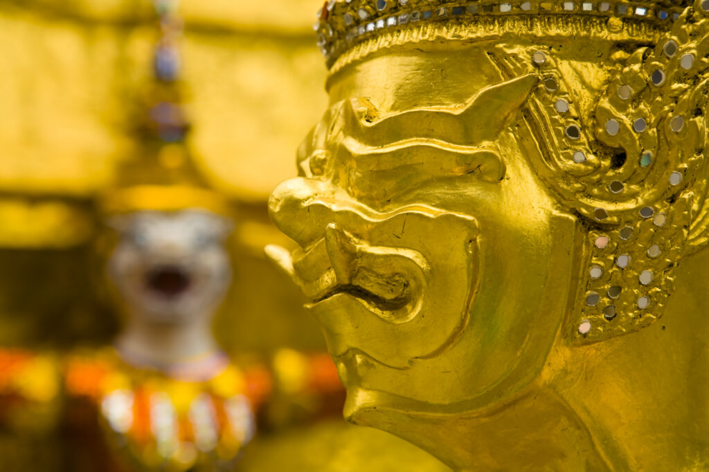 Thailand, Bangkok, The Grand Palace. Statue in the ornate setting of the golden grand palace.