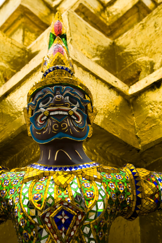 Thailand, Bangkok, The Grand Palace. Statue in the ornate setting of the golden grand palace.