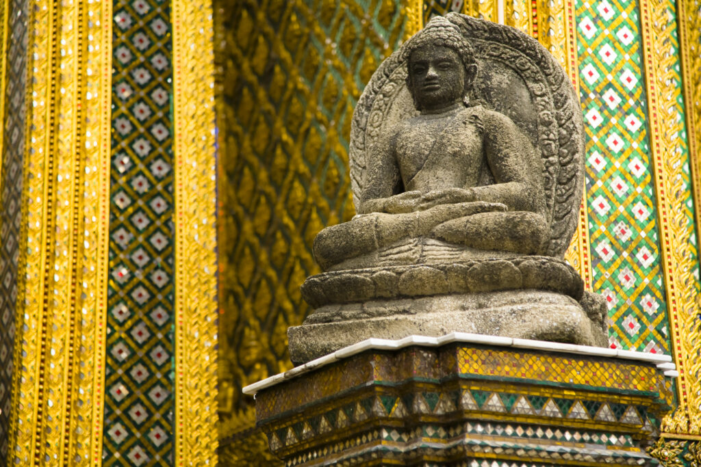 Thailand, Bangkok, The Grand Palace. Statue in the ornate setting of the golden grand palace.