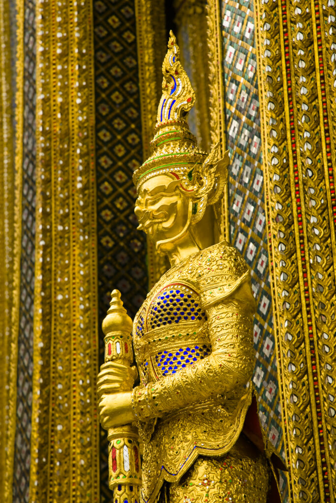 Thailand, Bangkok, The Grand Palace. Statue in the ornate setting of the golden grand palace.