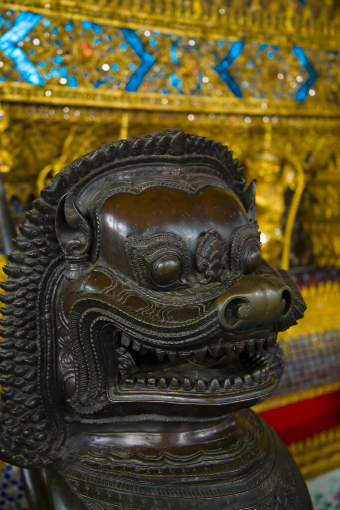 Thailand, Bangkok, The Grand Palace. Statue in the ornate setting of the golden grand palace.