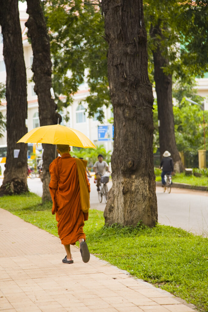 Cambodia, Siem Reap. Monk with umbrella walking along a street in Siem Reap near Angkor.