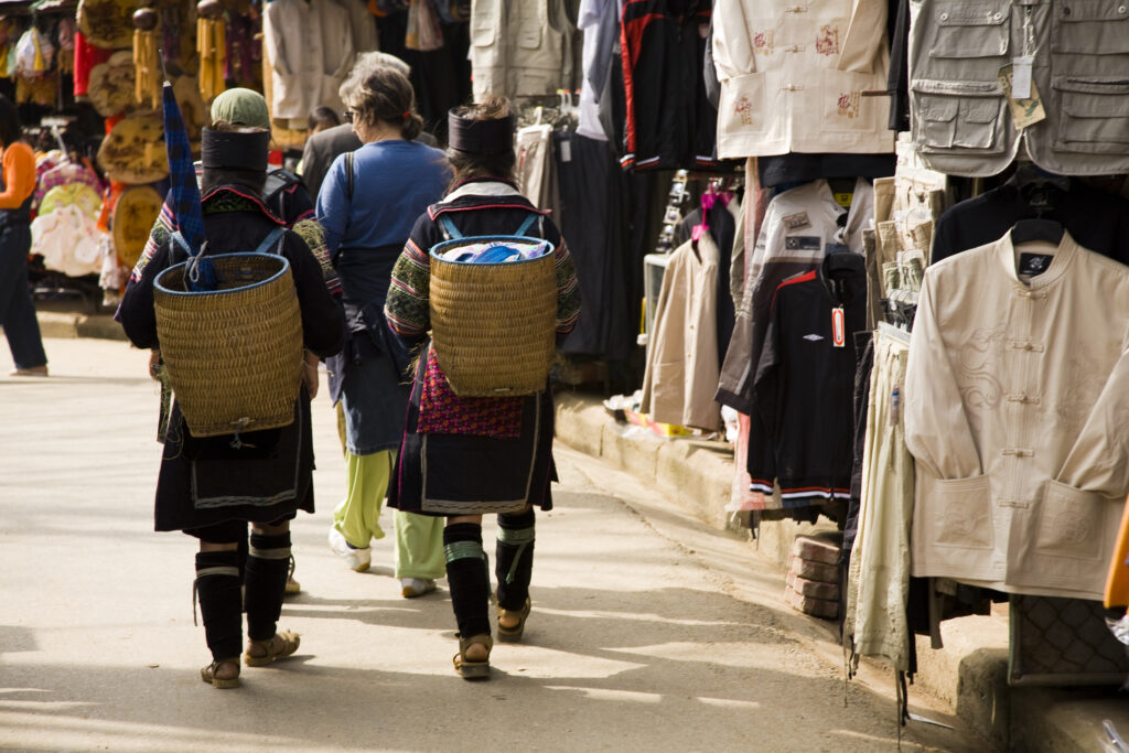 Vietnam, Northern Vietnam, Sapa. Local hill tribe women walk with baskets on their backs, through the Sapa square market.
