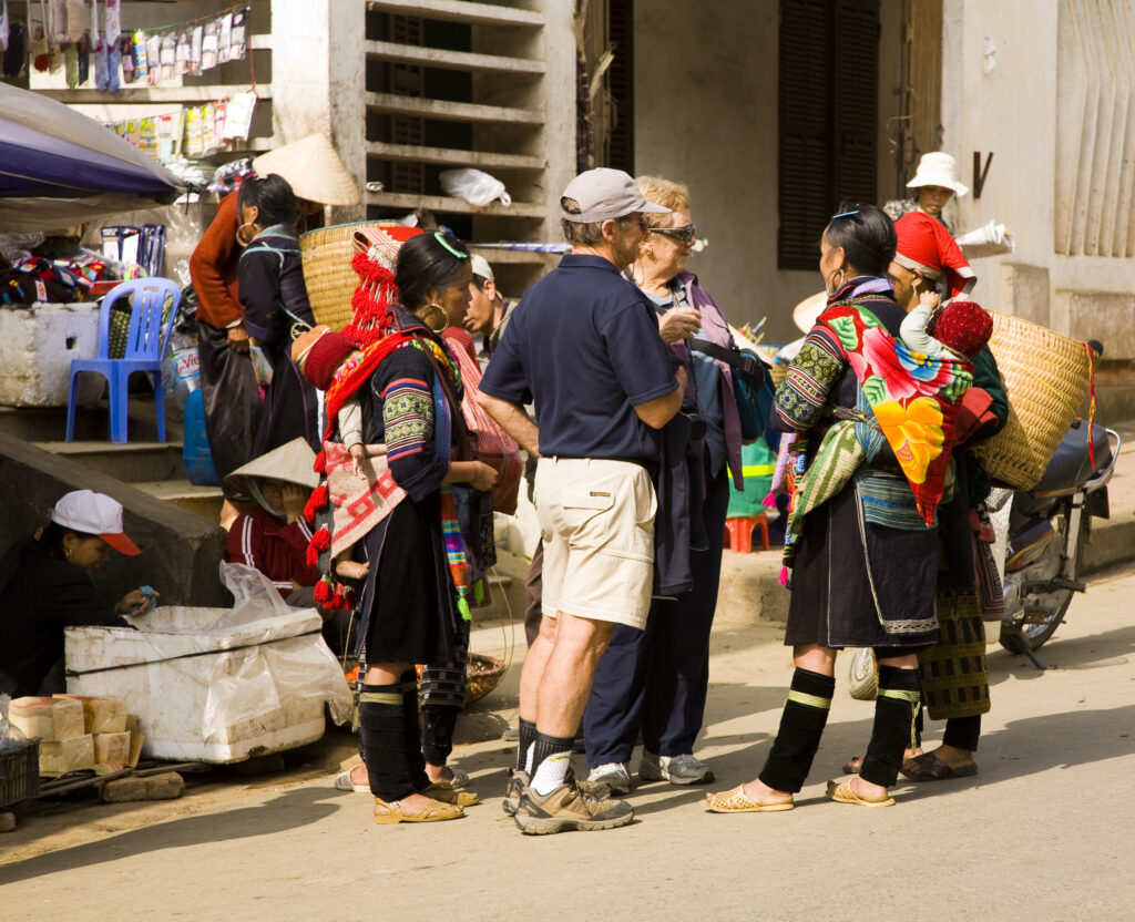 Vietnam, Northern Vietnam, Sapa. Local hill tribe women, complete with baskets and children on their backs, haggle with tourists as they try to secure a sale.