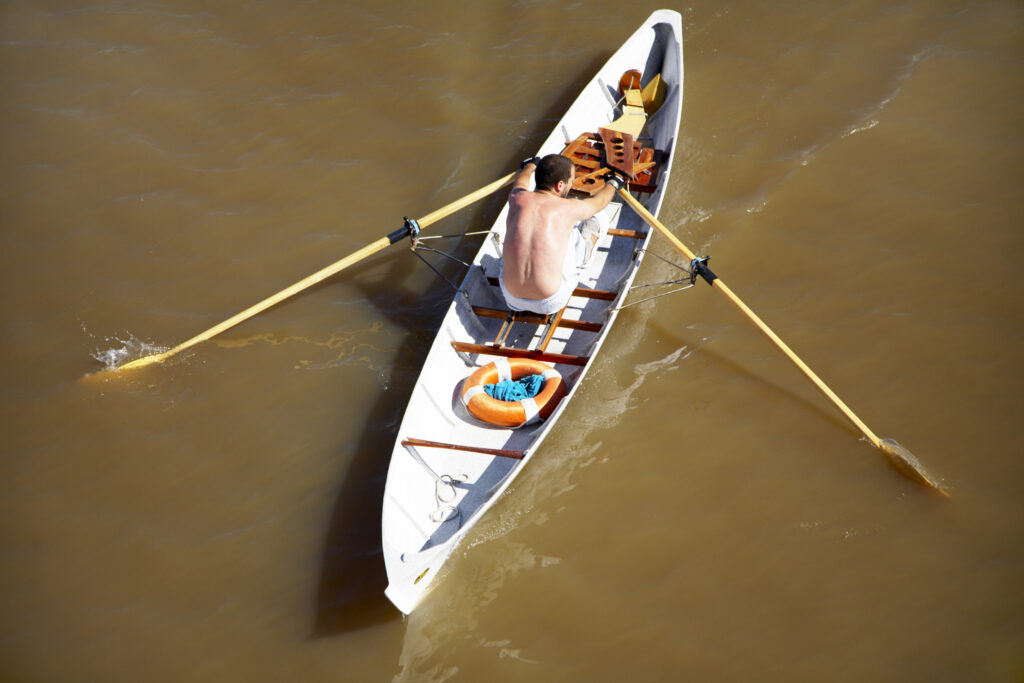 Argentina, Buenos Aires Province, Buenos Aires. Tourist rowing a canoe along a canal at the port of Puerto Madero.