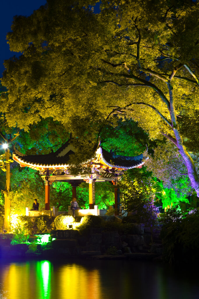 China, Guangxi Zhuang Autonomous Region, Guilin City. Pagoda and lake in downtown Guilin City, surrounded by trees floodlit with numerous colours.