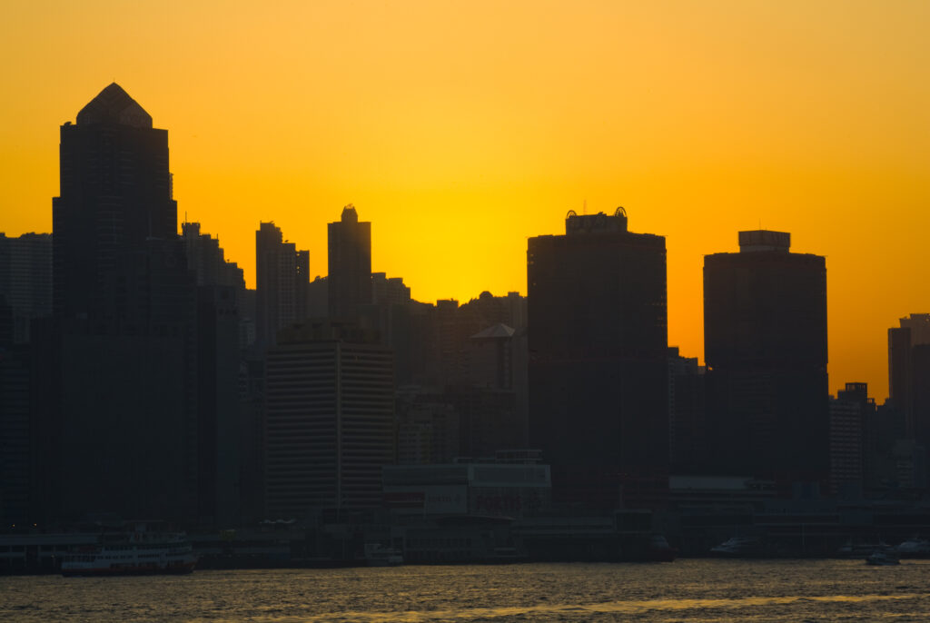 People's Republic of China, Hong Kong Special Administrative Region, Kowloon. The skyline of Kong Kong island viewed at sunset across Victoria Harbour from Kowloon.