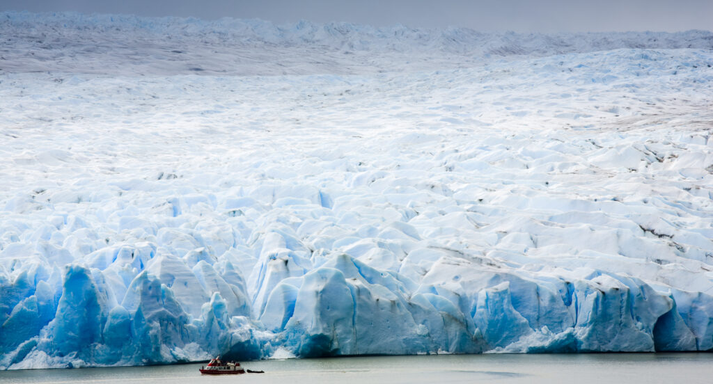 Chile, Southern Patagonia, Torres Del Paine National Park. Tourist boat on the Lago Grey dwarfed by the sheer ice wall of the Grey Glacier and the Patagonian Ice Field.