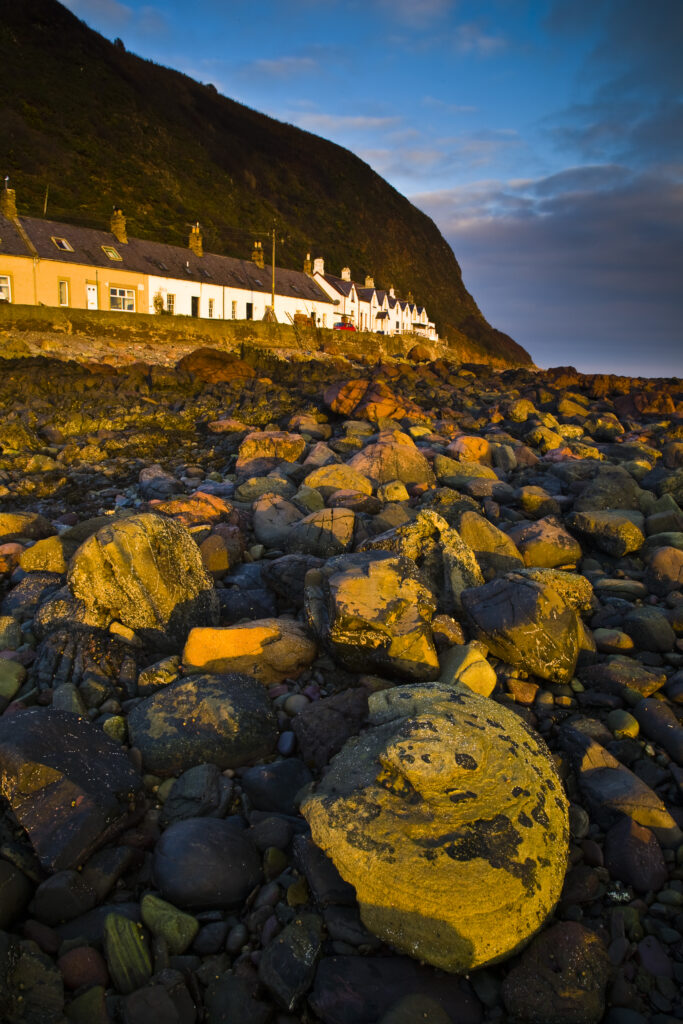 Scotland, Scottish Borders, Burnmouth. Early morning sun illuminates the rocky coastline to be found near the village of Burnmouth.
