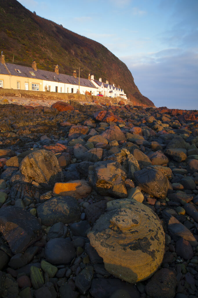 Scotland, Scottish Borders, Burnmouth. Early morning sun illuminates the rocky coastline to be found near the village of Burnmouth.