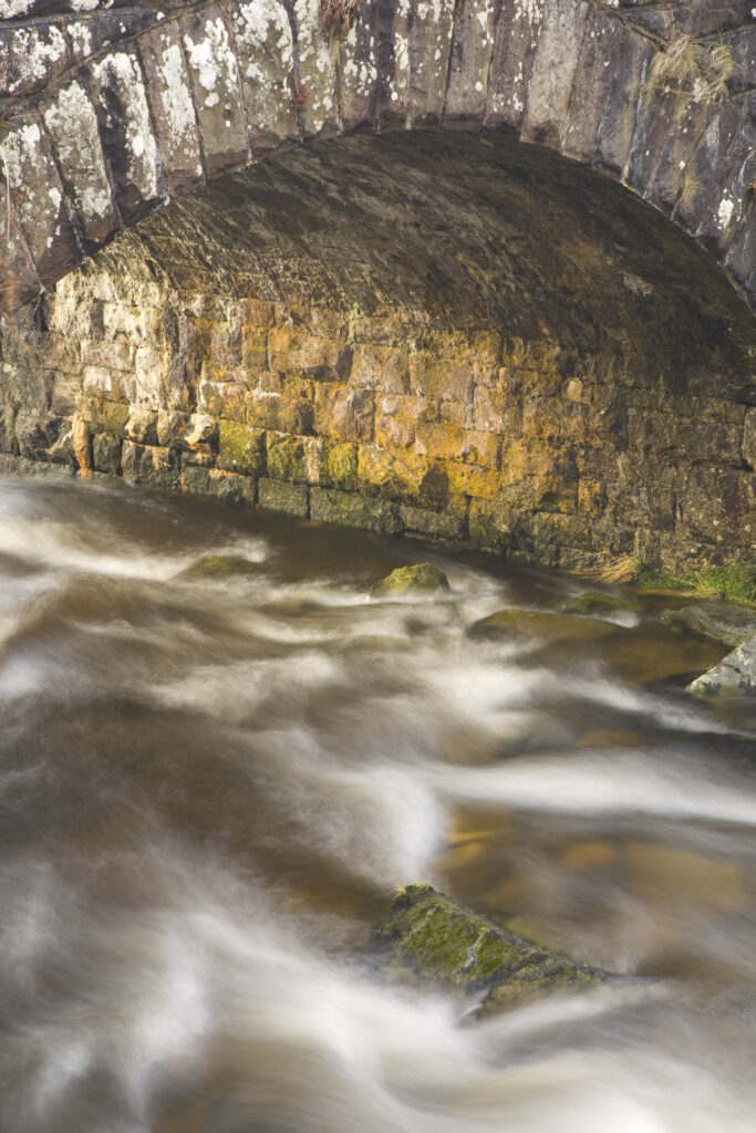 Scotland, Scottish Borders, Liddesdale. Liddel Water flowing through a bridge in Liddesdale.