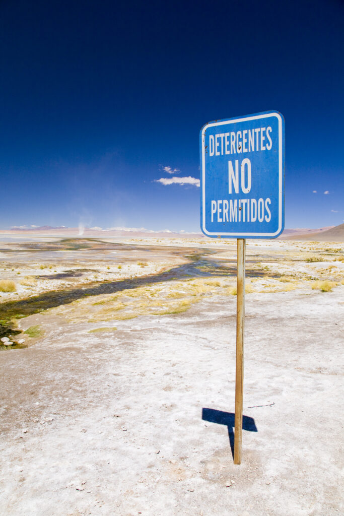 Bolivia, Southern Altiplano, Termas de Polques. Warning sign near a stream coloured by minerals at the Termas de Polques otherwise known as the Hot Pools.