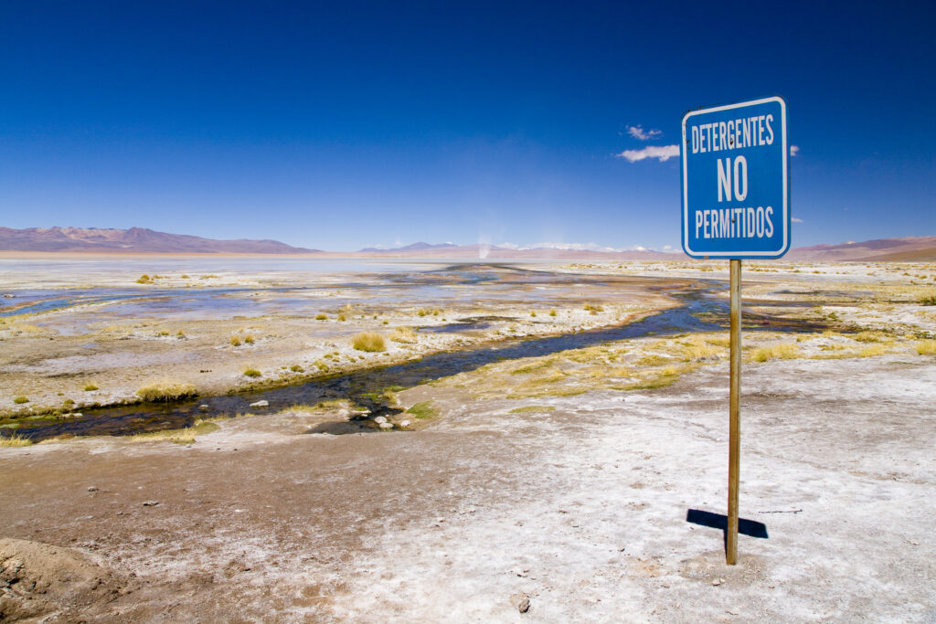 Bolivia, Southern Altiplano, Termas de Polques. Warning sign near a stream coloured by minerals at the Termas de Polques otherwise known as the Hot Pools.