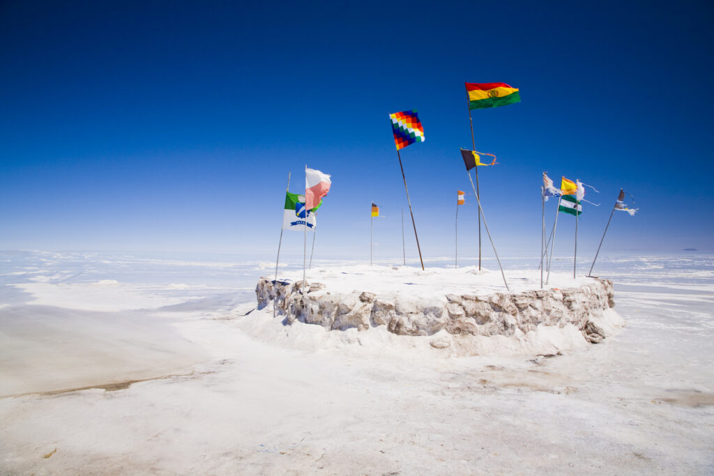 Bolivia, Southern Altiplano, Salar de Uyuni. Flags situated upon a mound of salt in the Salar de Uyuni salt flat.