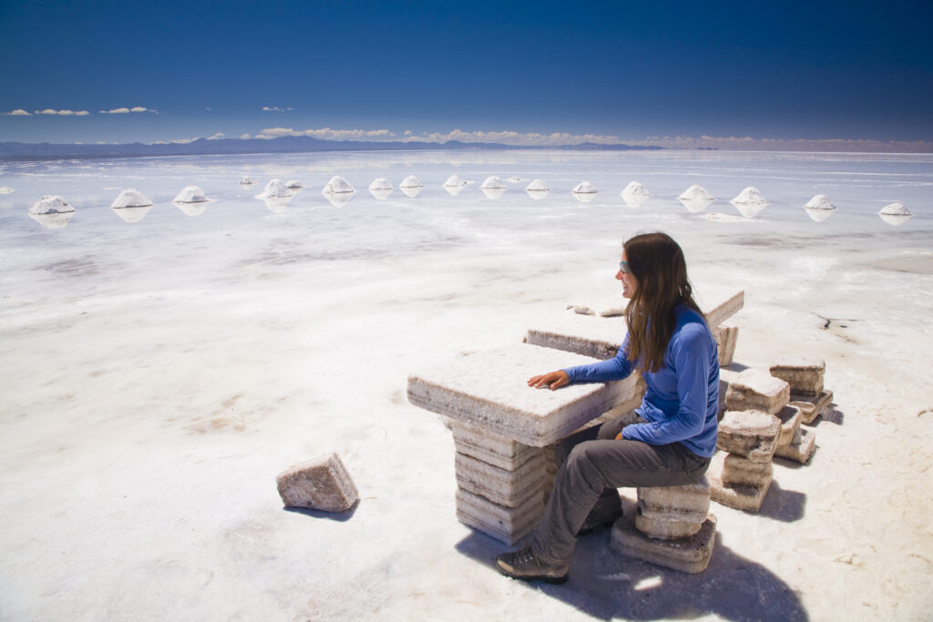 Bolivia, Southern Altiplano, Salar de Uyuni. Tourist resting on a seat constructed of salt, located on the Salar de Uyuni salt flat.