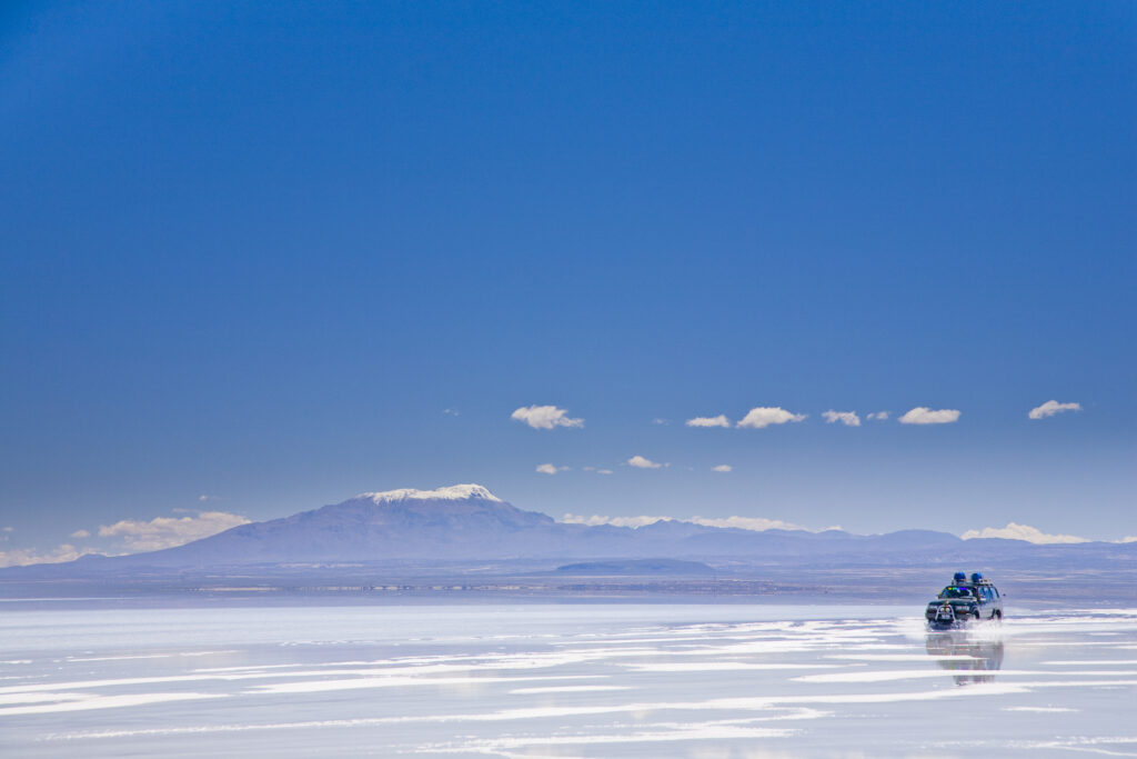 Bolivia, Southern Altiplano, Salar de Uyuni. Tourist jeep crossing the Salar de Uyuni salt flat.