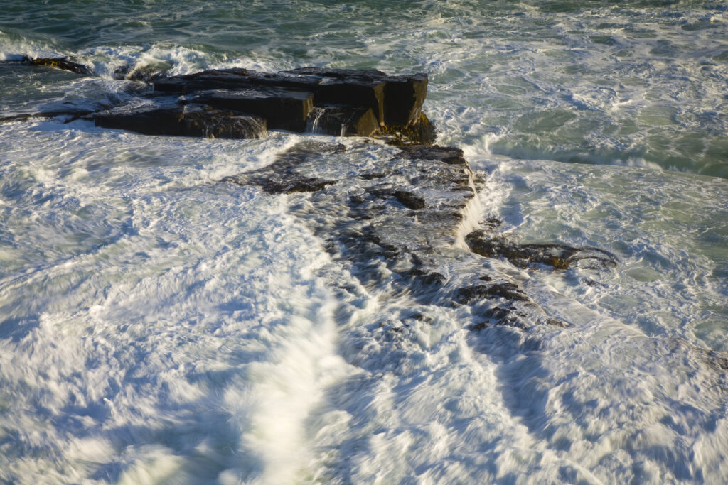 New Zealand, Southland, The Catlins. Waves crash on rocks near South Head, the headland seperating Curio Bay from Porpoise Bay.