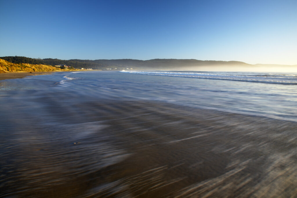 New Zealand, Southland, The Catlins. Looking across the golden sands of Porpoise Bay shortly after sunrise.
