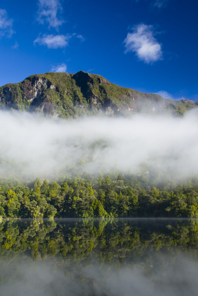New Zealand, Southland, Fiordland National Park. Autumn mist clears from Lake Alabaster, on the Hollyford Track.
