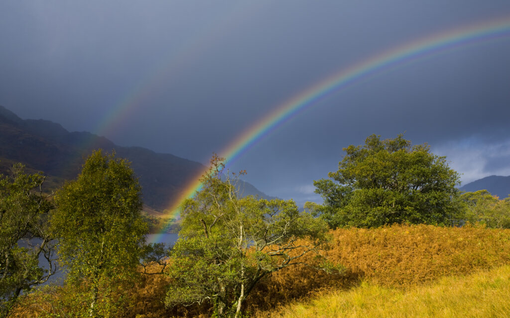 Scotland, Stirling, Loch Lomond and the Trossachs National Park. Rainbow over the banks of Loch Lomond and nearby mountains.