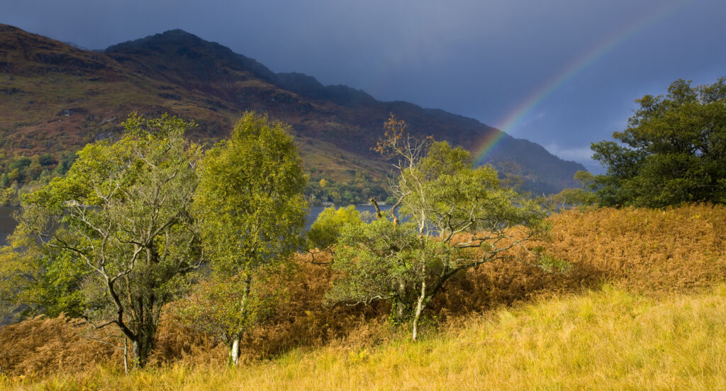 Scotland, Stirling, Loch Lomond and the Trossachs National Park. Rainbow over the banks of Loch Lomond and nearby mountains.