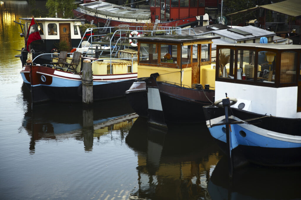 Netherlands, North Holland, Amsterdam. Boat houses moored on a canal near Oude Waal in Amsterdam City.
