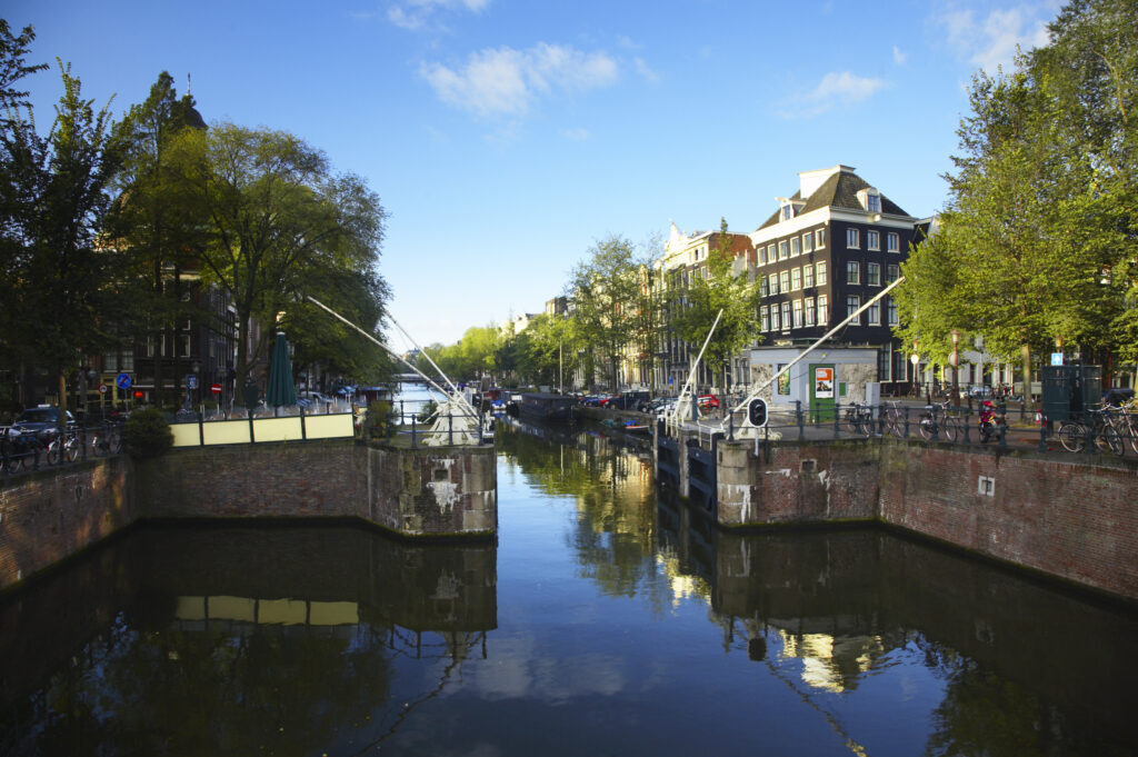 Netherlands, North Holland, Amsterdam. Typical architecture of Amsterdam city reflected in the still waters of an Amsterdam Canal.