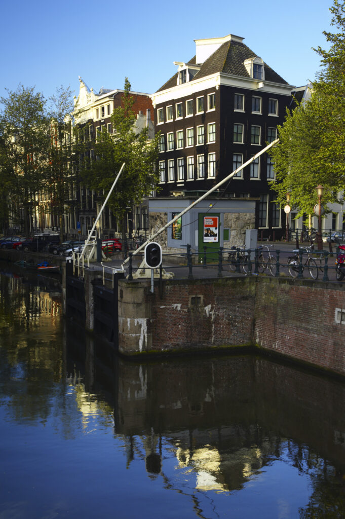 Netherlands, North Holland, Amsterdam. Typical architecture of Amsterdam city reflected in the still waters of an Amsterdam Canal.