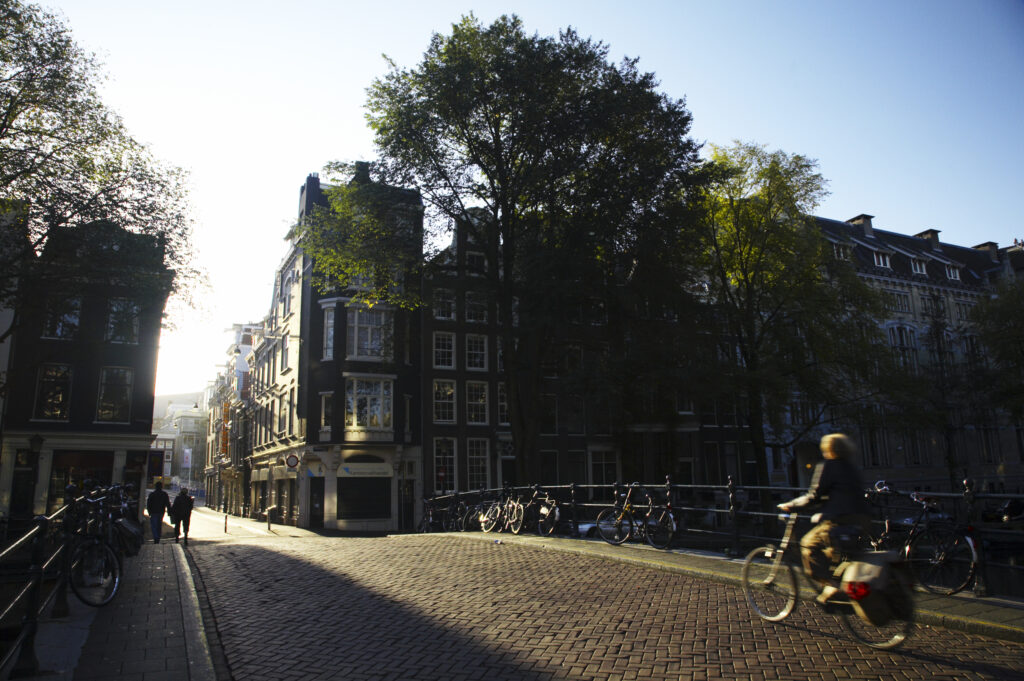 Netherlands, North Holland, Amsterdam. A cyclist crosses a bridge over a canal in Amsterdam City.