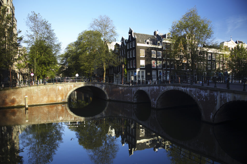 Netherlands, North Holland, Amsterdam. Typical architecture of Amsterdam city reflected in the still waters of an Amsterdam Canal.