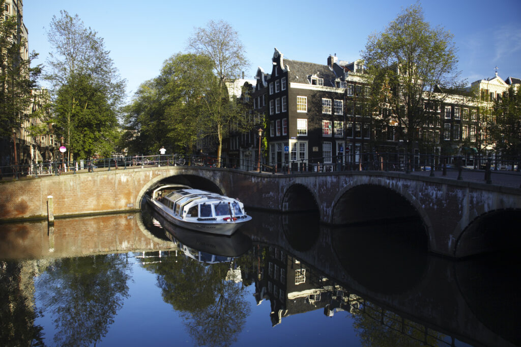 Netherlands, North Holland, Amsterdam. A canal sight seeing boat trip views the typical architecture of Amsterdam city reflected in the still waters of an Amsterdam Canal.