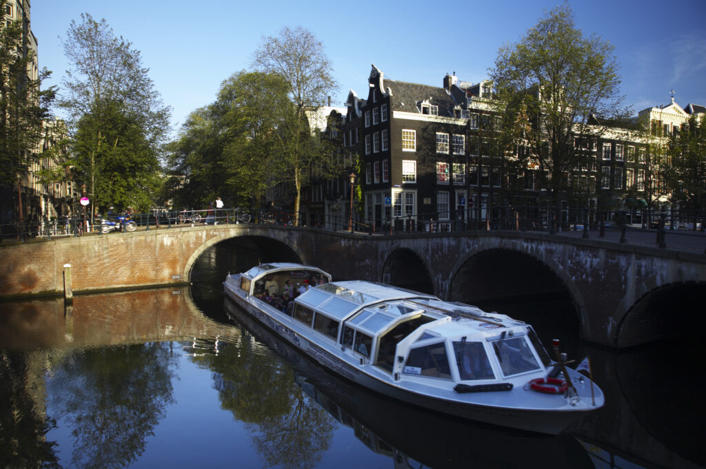 Netherlands, North Holland, Amsterdam. A canal sight seeing boat trip views the typical architecture of Amsterdam city reflected in the still waters of an Amsterdam Canal.