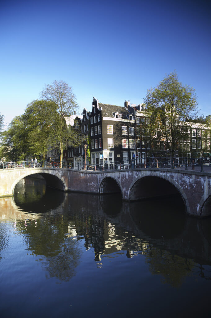 Netherlands, North Holland, Amsterdam. Typical architecture of Amsterdam city reflected in the still waters of an Amsterdam Canal.