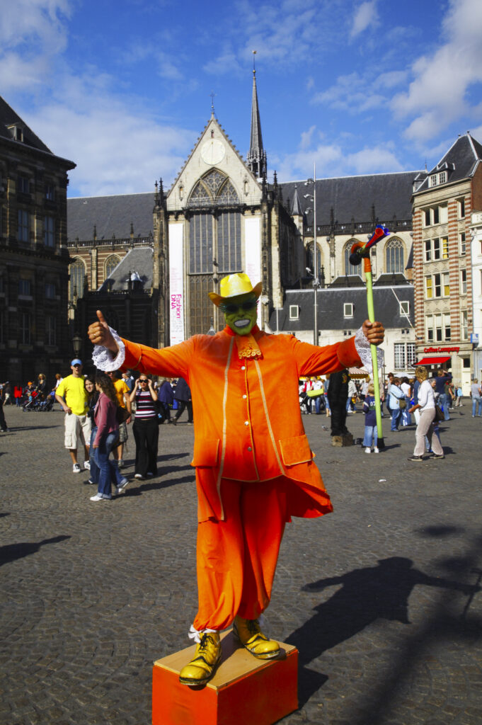 Netherlands, North Holland, Amsterdam. Street performer dressed as the Mask, outside Nieuwe Kerk (New Church) near the Royal Palace and Dam square in Amsterdam City.